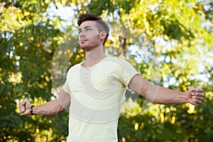 Attractive guy in the park extending his strong arms