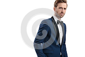 Attractive guy in tuxedo standing with hand in pocket