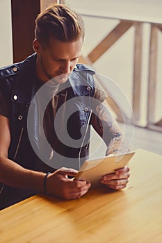 Attractive guy using a tablet PC in a cafe near the window.