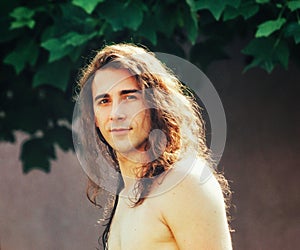 Attractive guy with very long hair is posing in the wild.