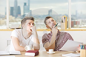 Attractive guys reading book and doing paperwork