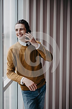 Attractive handsome young smiling executive worker man talking on the phone in office work station work place