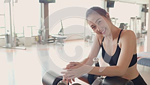 Attractive happiness sport woman resting and relaxing on fitness gym bench and smiling. People lifestyle and healthy activity and