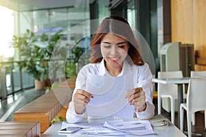Attractive happy Asian business woman smiling with document paper in her office background.