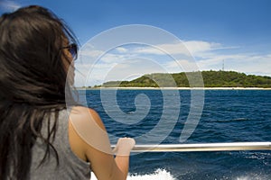 Attractive and happy Asian Chinese woman on excursion ship or ferry looking ocean and island enjoying sea breeze on summer holiday