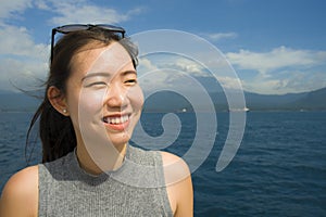 Attractive and happy Asian Chinese woman on excursion ship or ferry looking ocean and island enjoying sea breeze on summer holiday