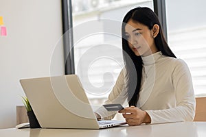 Attractive happy Asian woman online shopping with laptop, mobile, credit card and smartphone to shop with business idea concept ba