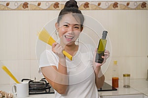 Attractive and happy Asian woman preparing noodles - domestic lifestyle portrait of young sweet and playful Korean girl at home