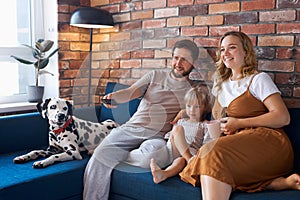 Attractive happy family with dog watch tv in living room