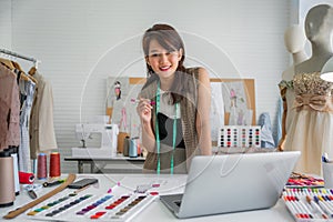 Attractive happy female designer dressmaker working sketch for trendy fashion in the workplace studio