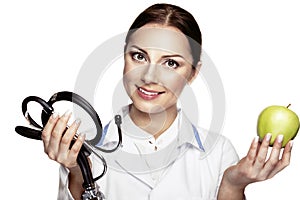 Attractive happy female doctor holding green apple and stethoscope and smiling.