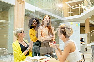 Attractive happy female employees greeting their new ginger colleague