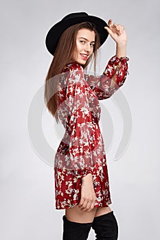 Attractive happy girl is possing and smilling in flower red dress and black hat on white