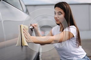 Attractive happy joyful female driver wipe her car using rag in self-service car wash