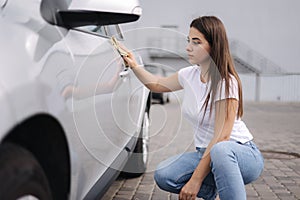 Attractive happy joyful female driver wipe her car using rag in self-service car wash