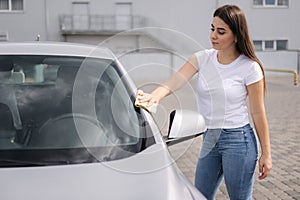 Attractive happy joyful female driver wipe her car using rag in self-service car wash