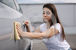 Attractive happy joyful female driver wipe her car using rag in self-service car wash. Focus on hand