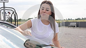 Attractive happy joyful female driver wipe windshield on her car using rag in self-service car wash