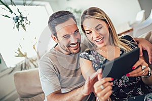 Attractive happy married couple using digital tablet