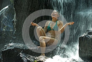 Attractive and happy mid adult woman with grey hair 40s or 50s enjoying blissful and free at beautiful tropical waterfall feeling