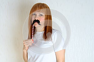 Attractive happy middle aged woman having fun with a fake moustache on stick.