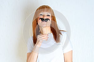 Attractive happy middle aged woman having fun with a fake moustache on stick.