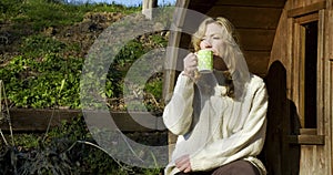 Attractive happy middle aged woman in her forties outside thoughtful, sad or depressed drinking a mug or cup of tea or coffee