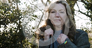 Attractive happy middle aged woman in her forties outside thoughtful, sad or depressed in golden winter sunshine