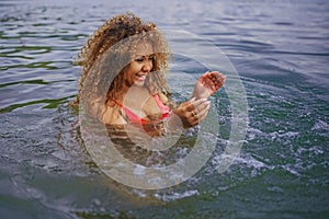 Attractive happy plus size African American Black woman enjoys swimming having fun with water splashes in sea lake water