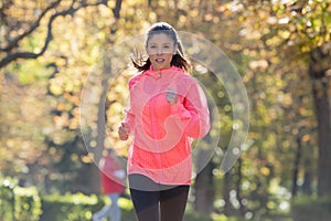 Attractive and happy runner woman in Autumn sportswear running a