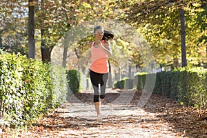 Attractive and happy runner woman in Autumn sportswear running and training on jogging outdoors workout in city park