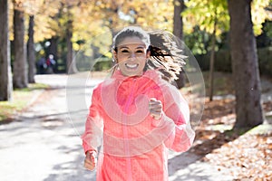 Attractive and happy runner woman in Autumn sportswear running and training on jogging outdoors workout in city park