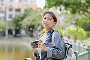 Attractive happy smile young adult asian woman traveller wear backpack. Using camera for photo journey