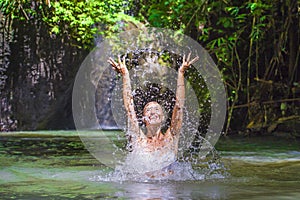 Attractive happy white tourist woman enjoying playing with water and splash at tropical exotic waterfall lagoon holidays travel co