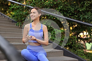 Attractive happy woman checking pulse with blood pressure monitor after training on stairs in park