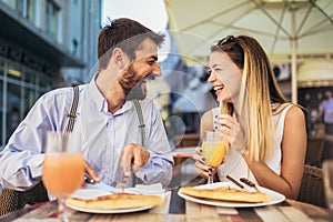 Happy young couple having good time in cafe restaurant. They are smiling and eating a pizza