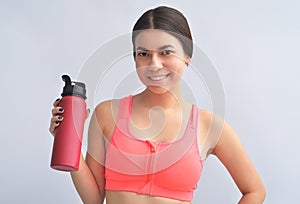 Attractive happy young fit sportswoman standing  over gray background