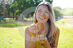 Attractive healthy young woman eating Brazil nuts in park on summe