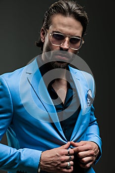 attractive high class man with glasses unbuttoning blue suit