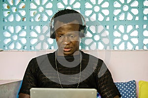 Attractive and hipster black African American business man networking with laptop computer and headphones concentrated and