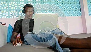 Attractive and hipster black African American business man networking with laptop computer and headphones concentrated and