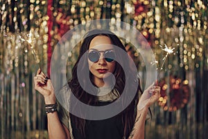 Attractive hipster girl holding sparklers in hands