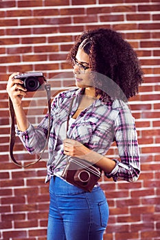 Attractive hipster holding camera and looking at it