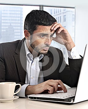 Attractive Hispanic businessman working with computer looking stressed and worried facing work issue