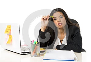 Attractive hispanic businesswoman or secretary suffering breakdown and headache in stress at office