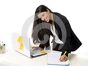 Attractive hispanic businesswoman or secretary taking notes standing leaning on office computer desk