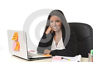 Attractive hispanic businesswoman sitting at office desk working on computer laptop smiling happy