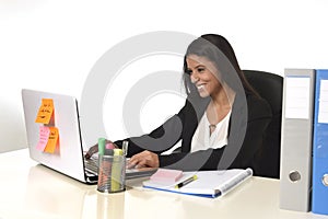 Attractive hispanic businesswoman sitting at office desk working on computer laptop smiling happy