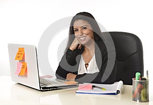 Attractive hispanic businesswoman sitting at office desk working on computer laptop smiling happy