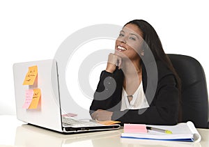 Attractive hispanic businesswoman sitting at office desk working on computer laptop smiling happy